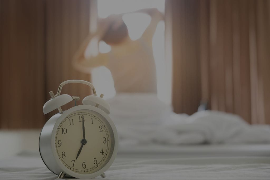 Woman waking up to alarm clock in front of window